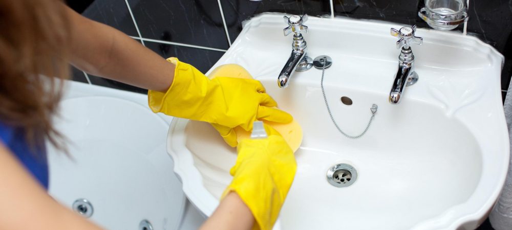 girl cleaning the sink while wearing a gloves